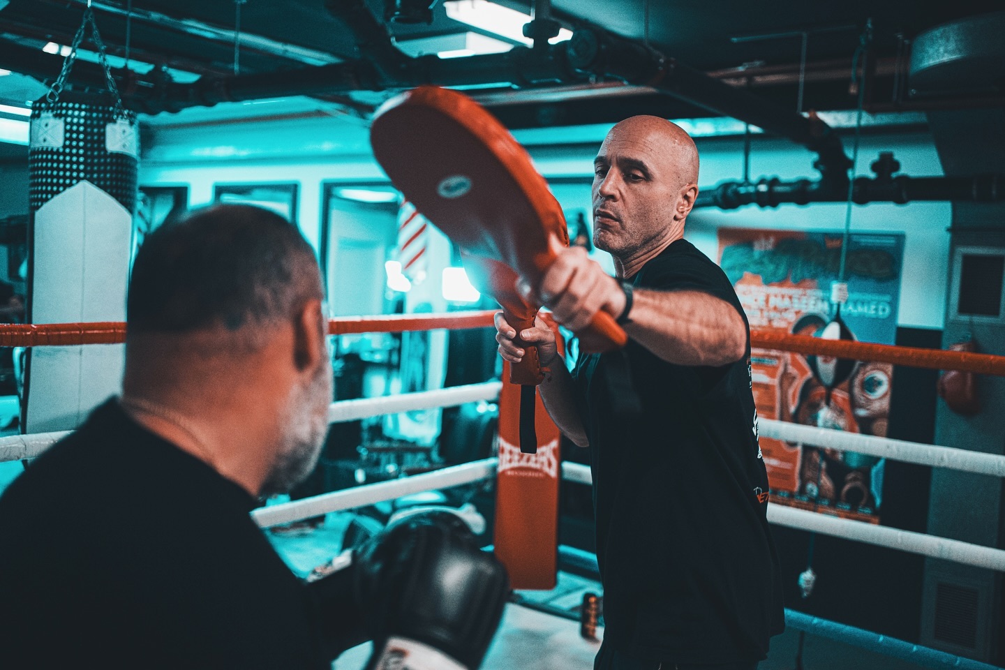 Boxing coach training a fighter with pads, gym setting