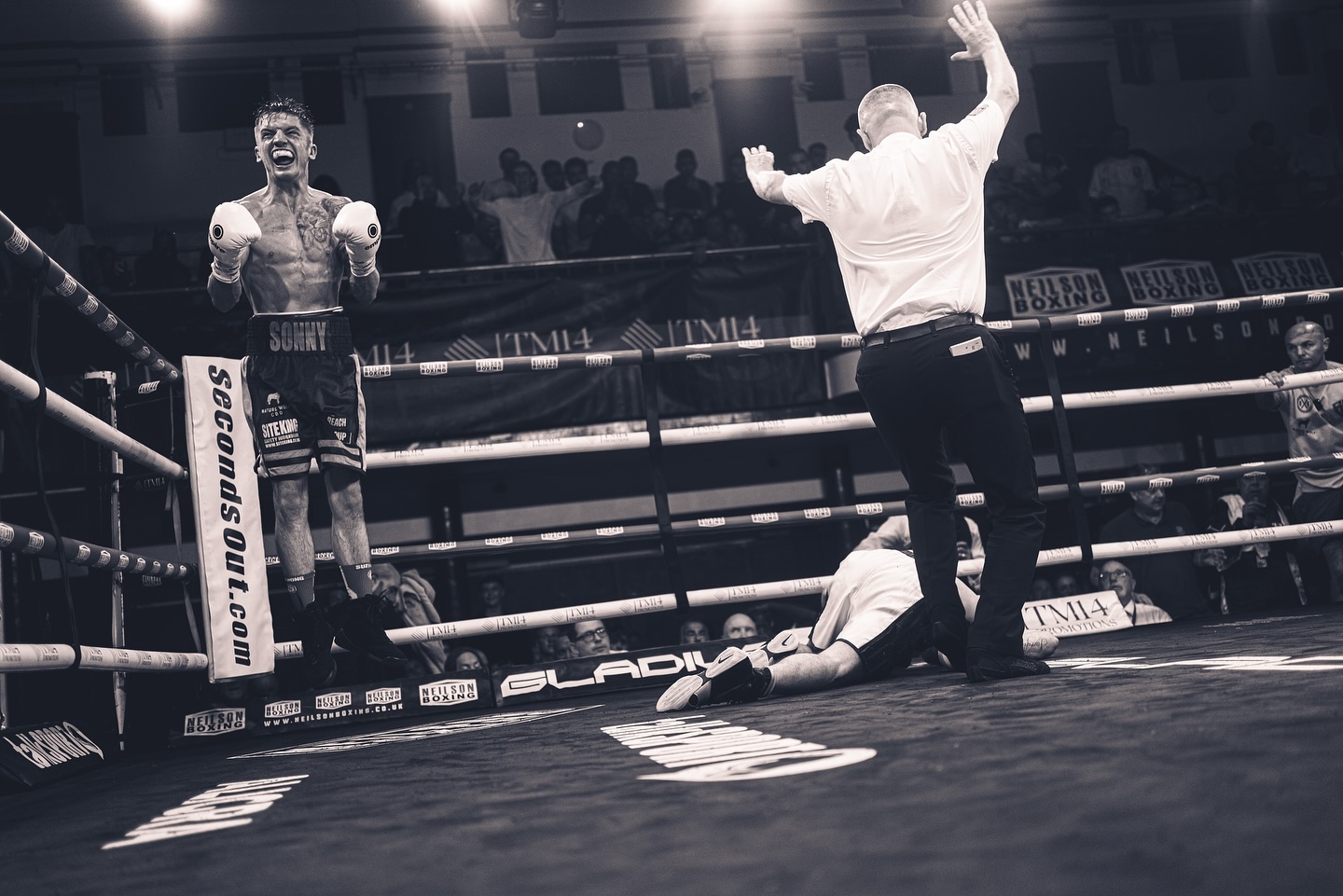 Referee counting over a fallen boxer, black and white